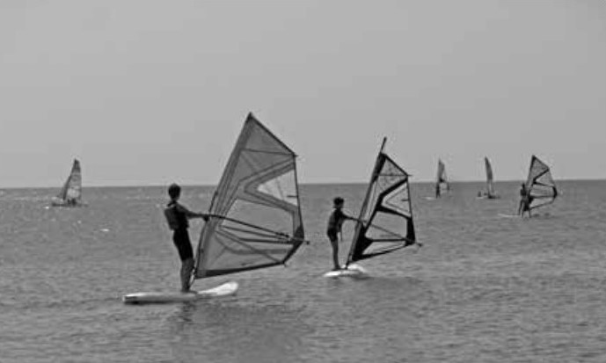 Fotografia de praticantes de windsurf numa praia
